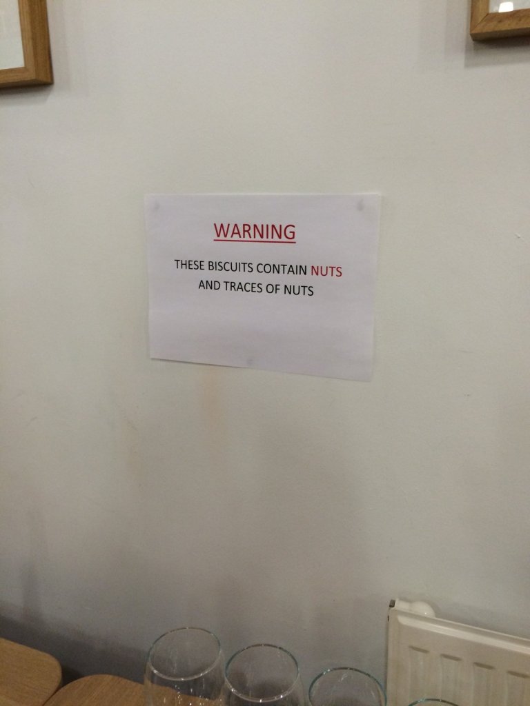 A sign taped to a wall: Warning. These biscuits contain nuts and traces of nuts.