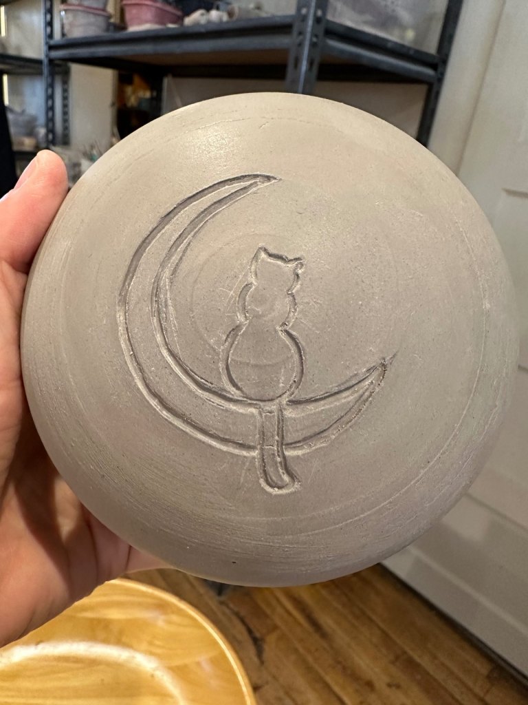 Close-up of the carved cat sitting on a crescent moon