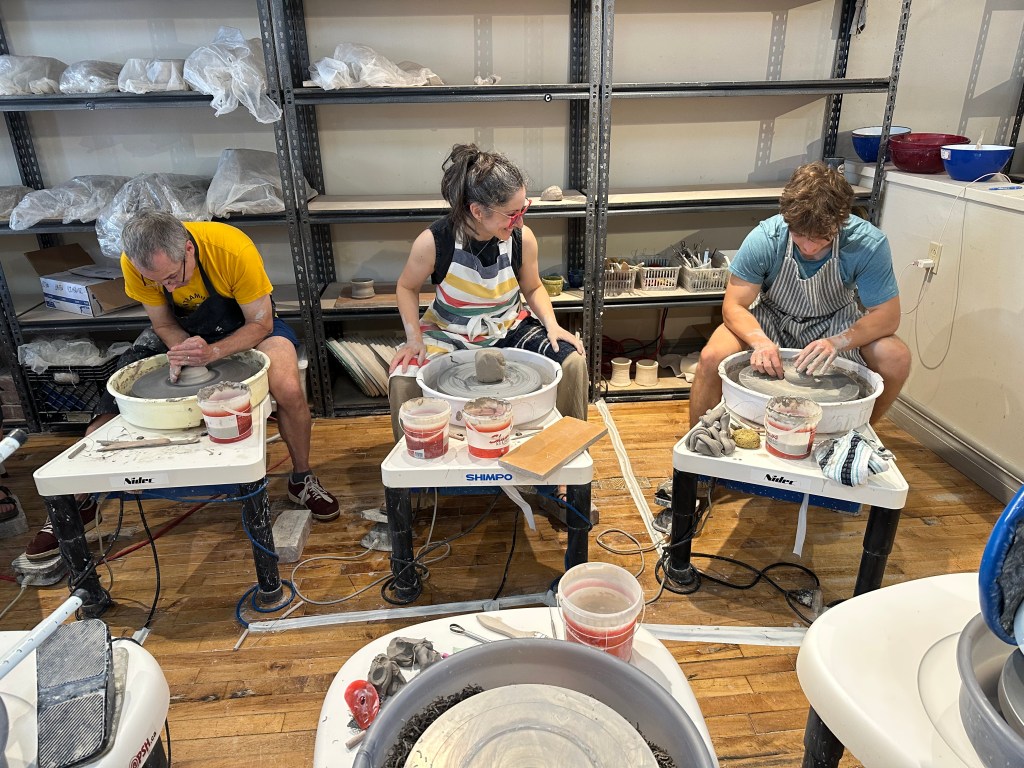 Robyn showing Ed and Max how to throw on the pottery wheel