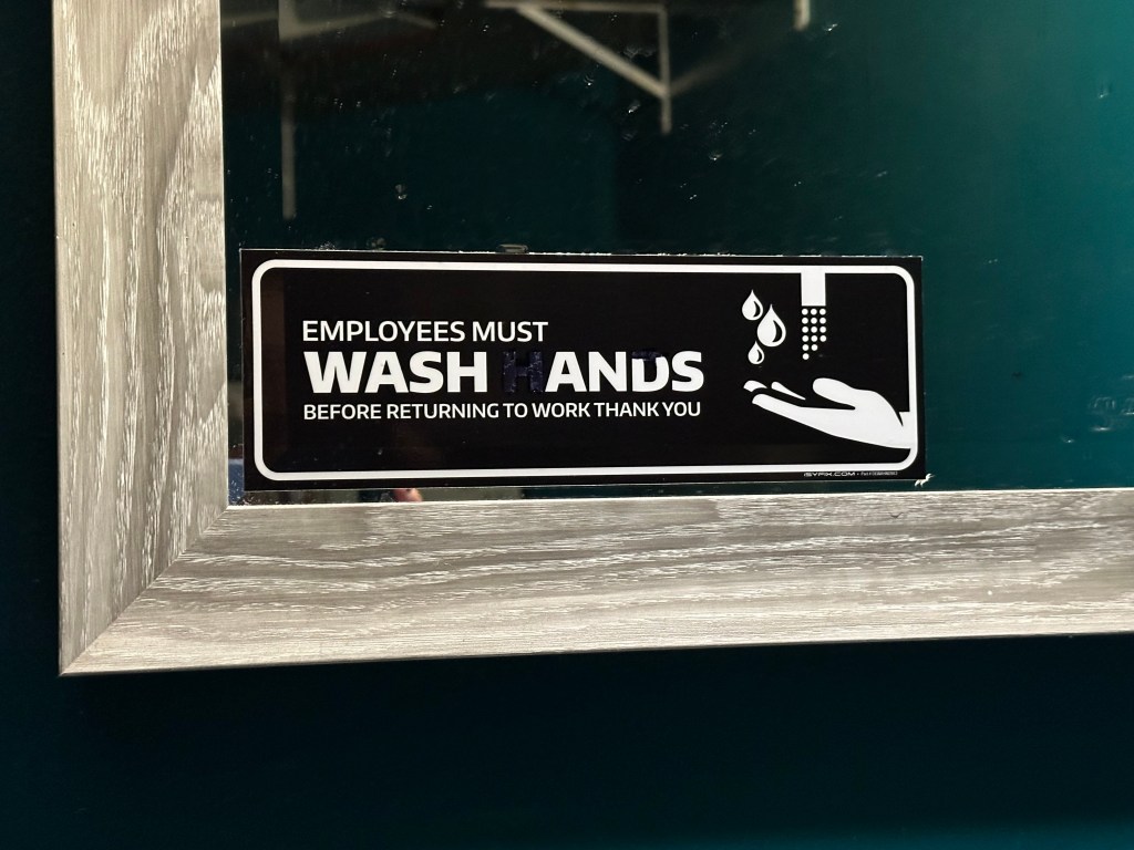 Photograph of a sign, titled Wash anus?
