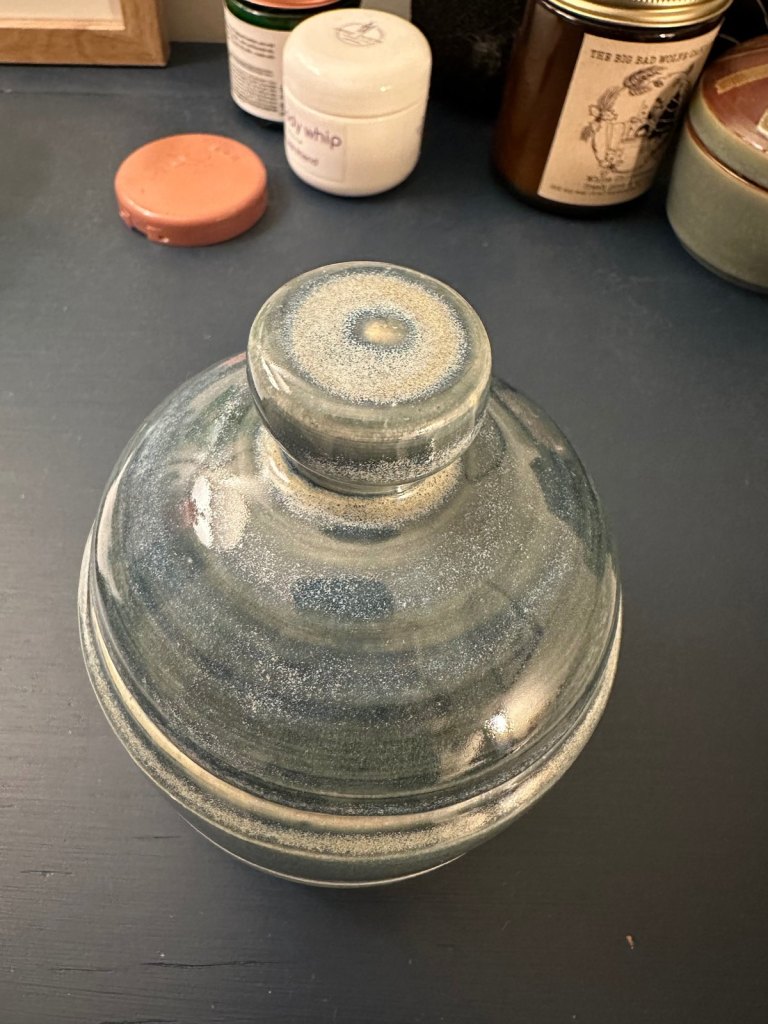 The lidded jar seen from above, its glaze breaking into speckled rings