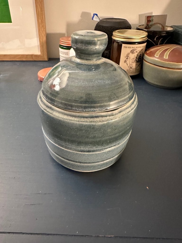 A lidded jar with a knob handle, glazed in layered blue-grey