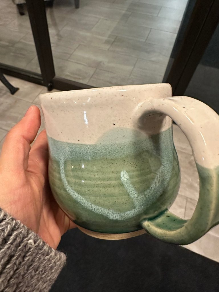A round-bellied mug, white above and green below, with a pale glaze drip pattern